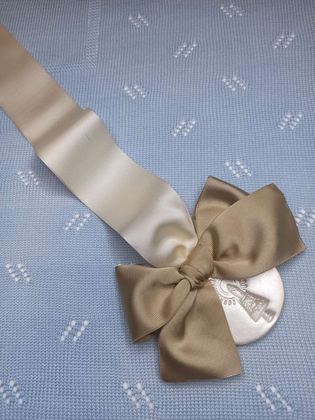 La Medalla de la Virgen del Pilar de Zaragoza con cinta beige y lazo tostado es un símbolo de protección y ternura para acompañar a tu bebé desde sus primeros días. Perfecta para la cuna, minicuna o carro, su diseño delicado en tonos suaves transmite calma, tradición y elegancia.